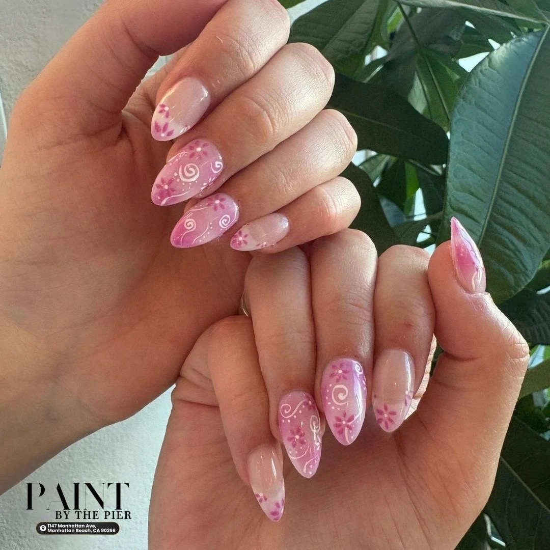 Almond-shaped pink swirl nails with delicate white daisy floral art - Paint by the Pier Manhattan Beach